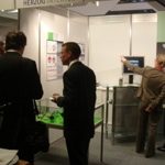 Customer discussion in front of the HERZOG INTERTEC stand at the 17th Aachen Colloquium for Vehicle and Engine Technology